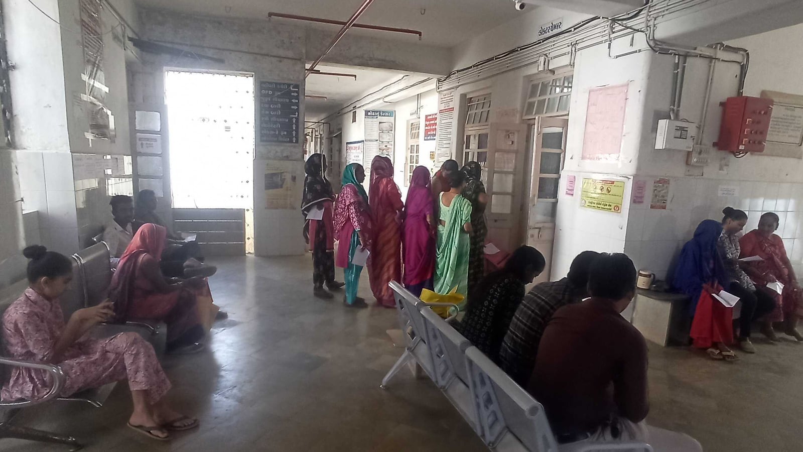 Women waiting on benches and queuing with referral slips outside a consulting room at a community health centre